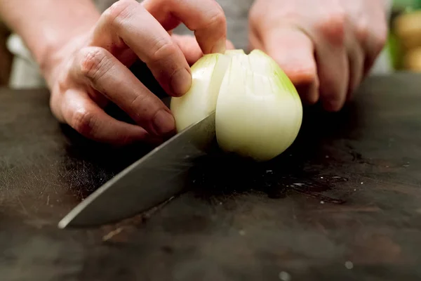 Snijden van uien op een snijplank in de keuken. — Stockfoto