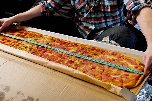Измерьте длину пиццы с помощью рулетки — стоковое фото
