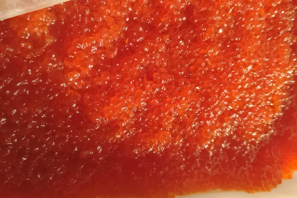 Mélanger les œufs avec la main gantée. caviar rouge dans un récipient en plastique . — Photo