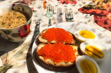 Kırmızı havyarlı sandviç, haşlanmış yumurta, kahve fincanı. Günaydın.