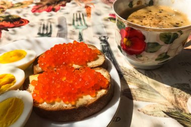 Kırmızı havyarlı sandviç, haşlanmış yumurta, kahve fincanı. Günaydın.