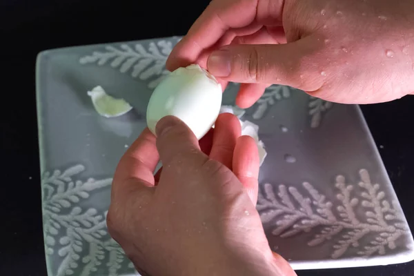 Καθαρίζει ένα βραστό αυγό. Ένας άντρας καθαρίζει αυγά για πρωινό.. — Φωτογραφία Αρχείου