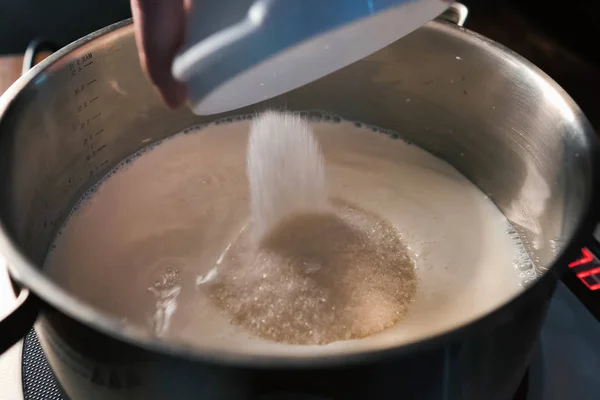 Наливаючи цукор в молоко на сковороду на лусках . — стокове фото