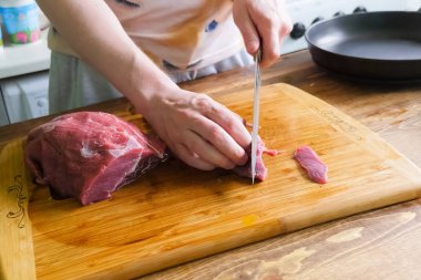 Bıçak, domuz eti parçaları ile bir kesme tahtası üzerinde domuz dilimleme