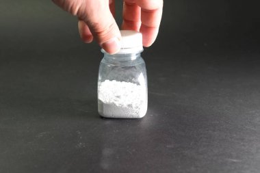 Şeffaf kavanozda beyaz toz. Masanın üzerinde beyaz toz.