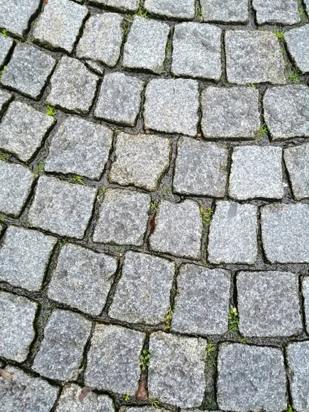 Old road paved with granite stones texture background