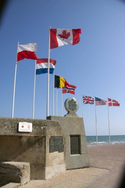 Courseulles-Sur-Mer, Fransa. 25 Temmuz 2018: İkinci Dünya Savaşı sırasında Nazizm ve faşizme karşı müttefik ülkelerin ulusal bayrakları, 1944 yılında Normandiya 'nın karaya çıktığı Juno Beach' te. Anıt Kanadalı askerler.