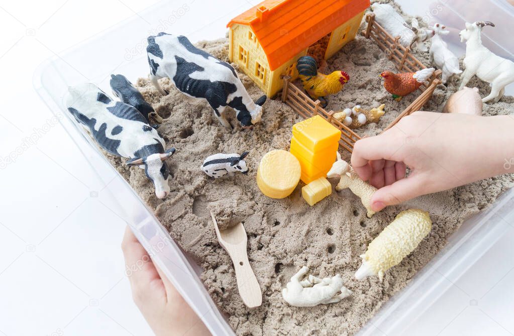 Montessori material. Children's hands play an animal figure. Kinetic sand