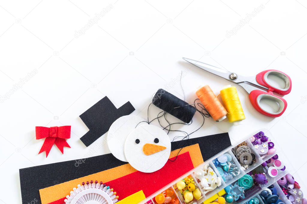 We sew a toy snowman made of felt. Christmas symbol.