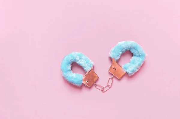 Esposas con pelo azul juguetes sexuales para adultos, diseño minimalista, aislado sobre un fondo rosa . — Foto de Stock
