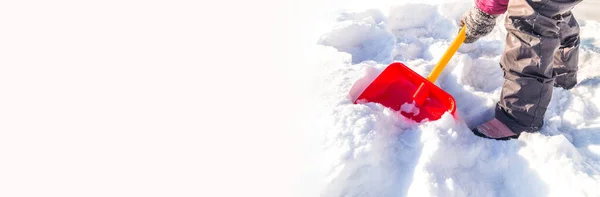 El niño cava una pala de nieve. El chico con las manos en manoplas sostiene una pala roja. Copia spase Banner — Foto de Stock