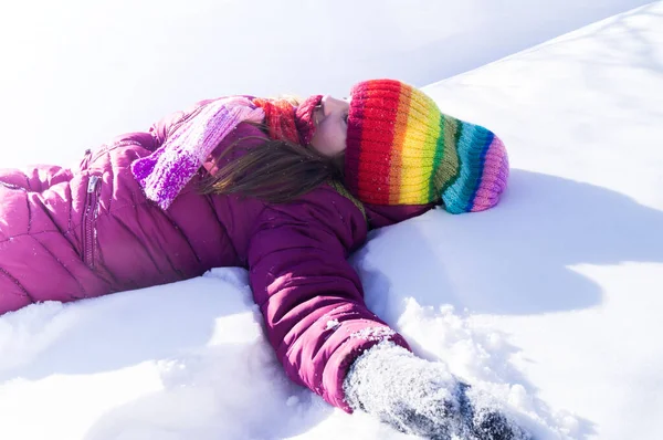 El niño yace boca arriba en la nieve. Emoción chica en un paseo. Vacaciones de invierno. Juegos al aire libre . — Foto de Stock