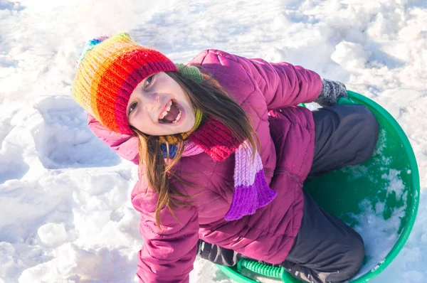 Un niño baja por una colina nevada. Emoción chica en un paseo. Vacaciones de invierno. Juegos al aire libre . — Foto de Stock