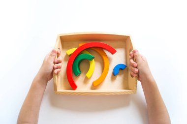 Montessori ahşap gökkuşağı malzemesi. Bir çocuk elleriyle bir oyuncakla oynar..