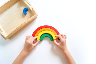 Montessori ahşap gökkuşağı malzemesi. Bir çocuk elleriyle bir oyuncakla oynar..