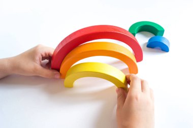 Montessori ahşap gökkuşağı malzemesi. Bir çocuk elleriyle bir oyuncakla oynar..