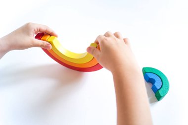 Montessori ahşap gökkuşağı malzemesi. Bir çocuk elleriyle bir oyuncakla oynar..