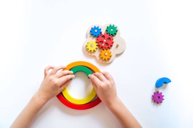 Montessori ahşap gökkuşağı malzemesi. Bir çocuk elleriyle bir oyuncakla oynar..