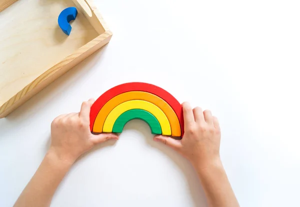 Montessori ahşap gökkuşağı malzemesi. Bir çocuk elleriyle bir oyuncakla oynar..