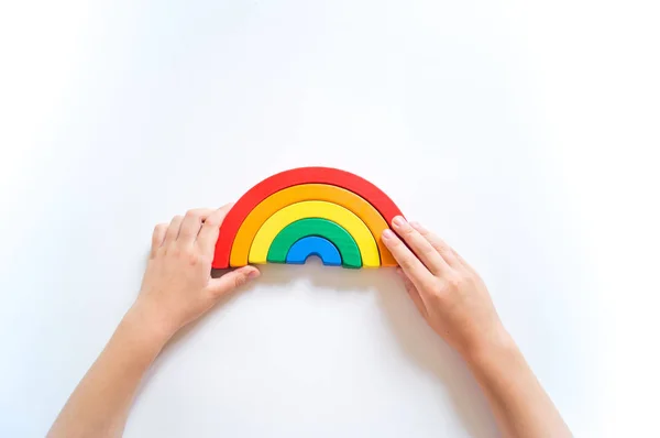 Materiale arcobaleno in legno Montessori. Un bambino gioca con un giocattolo con le mani . — Foto Stock