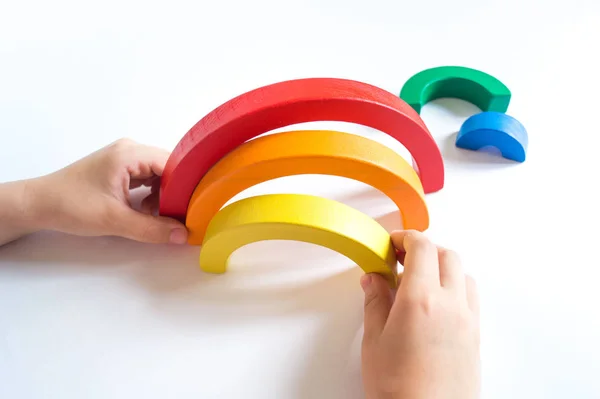 Materiale arcobaleno in legno Montessori. Un bambino gioca con un giocattolo con le mani . — Foto Stock