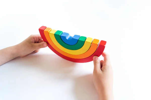 Material de madera Montessori arco iris. Un niño juega con un juguete con las manos . — Foto de Stock