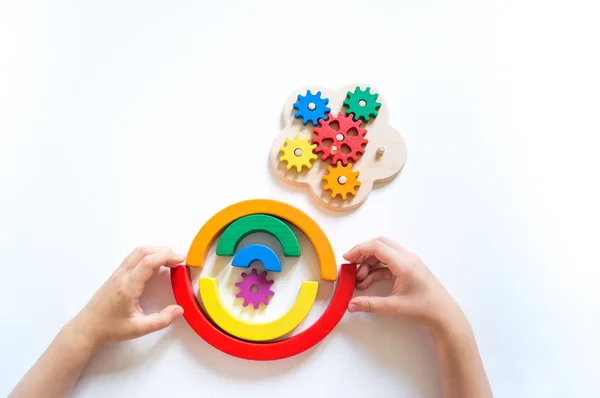 Montessori Holz Regenbogenmaterial. ein Kind spielt mit seinen Händen mit einem Spielzeug. — Stockfoto