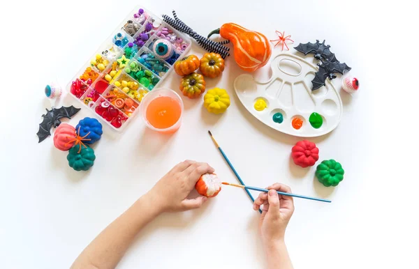 A criança pinta uma abóbora decorativa com a pintura. Férias de Halloween . — Fotografia de Stock