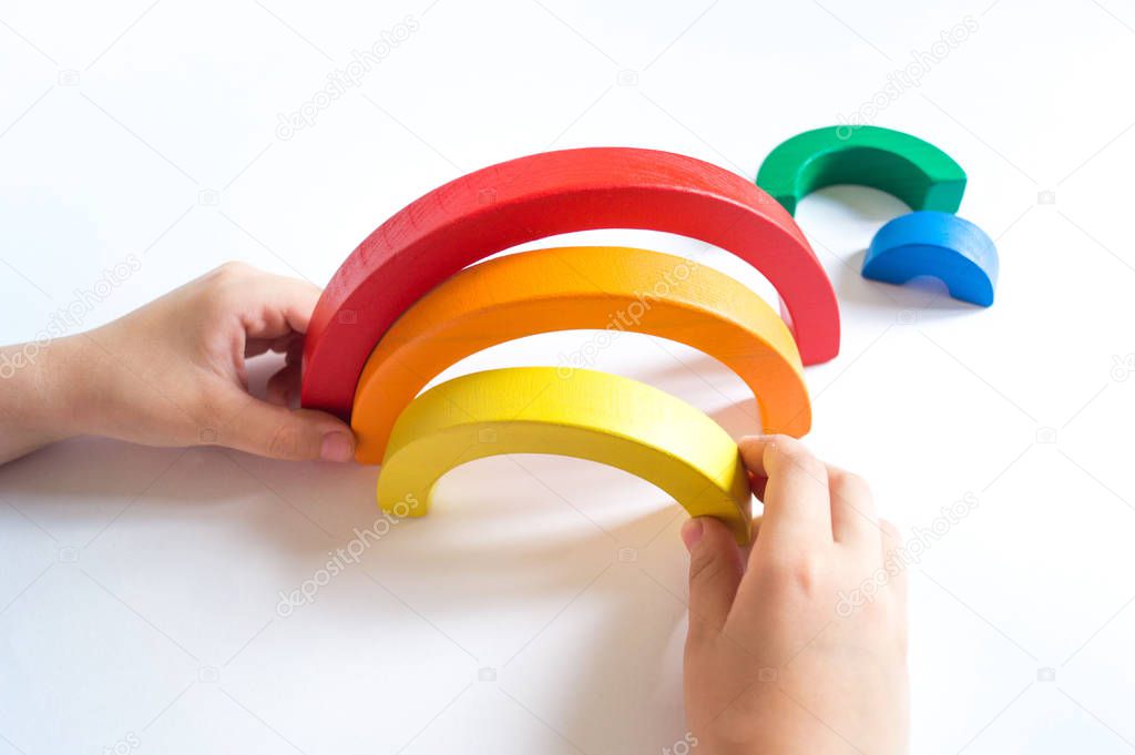 Montessori wood rainbow material. A child plays with a toy with his hands.
