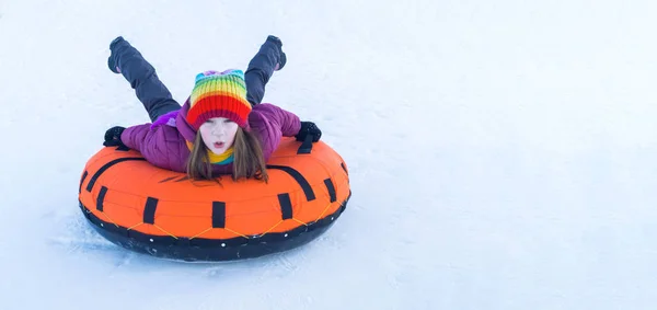 Молодая улыбающаяся девушка катается на санях снежные трубки — стоковое фото