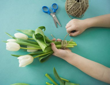 Hands of a child make a bouquet of tulips.