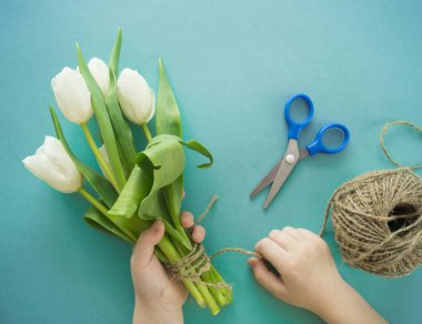 Hands of a child make a bouquet of tulips.