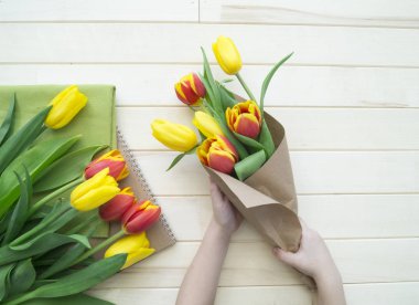 Hands of a child make a bouquet of tulips.