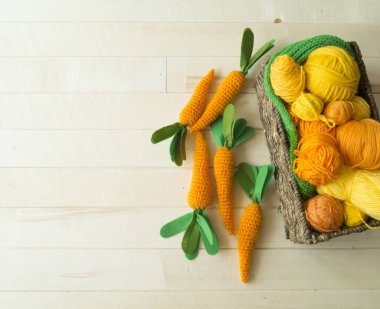 Örgü havuç. Sepetteki iplikler ve örgü iğneleri. Paskalya için oyuncak üretme süreci.