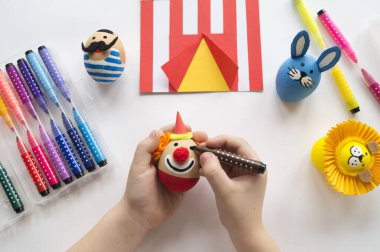 Paskalya tatili. Çocukların elleri yumurta boyar. Dekorun masadaki hazırlığı.