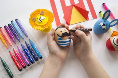 Paskalya tatili. Çocukların elleri yumurta boyar. Dekorun masadaki hazırlığı.