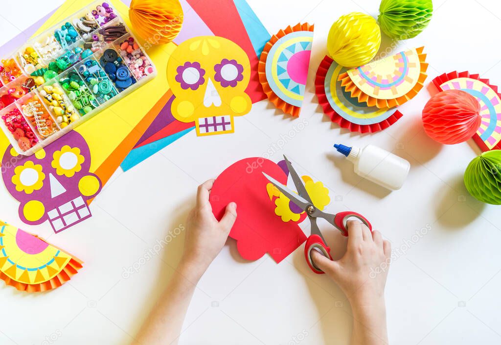 Holiday Cinco de mayo Mexican. Decoration for the festival. Garland skull painted with patterns. Hands of a child.