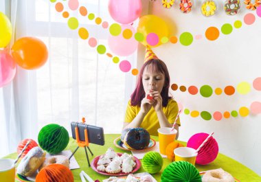 Video konferansındaki arkadaşıyla birlikte sanal doğum günü partisinde. Çevrimiçi toplantı için dijital telefonla. Karantina zamanında doğum gününü kutlayan kız