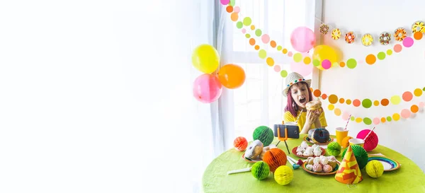 Children virtual birthday party with cake online together with her friend in video conference. With digital telephone for a online meeting. Girl celebrating birthday online in quarantine time