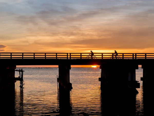 Silhueta de ciclistas na ponte, hora do pôr-do-sol — Fotografia de Stock