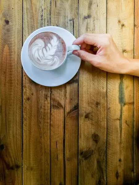 Chocolate quente em uma xícara branca, na mesa de madeira, mão tentar escolher um — Fotografia de Stock