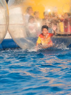 İçinde bir yüzen su topu yürüyüş oynayan genç Asyalı çocuk