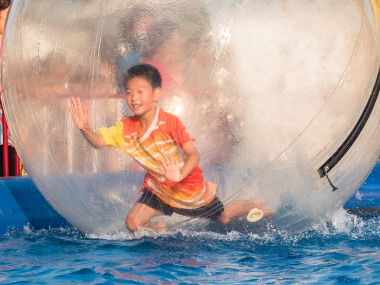 İçinde bir yüzen su topu yürüyüş oynayan genç Asyalı çocuk