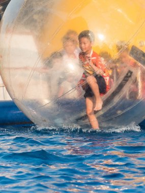 İçinde bir yüzen su topu yürüyüş oynayan genç Asyalı çocuk