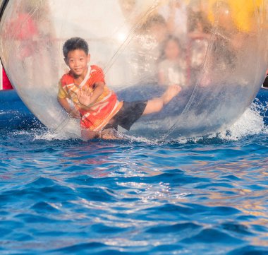 İçinde bir yüzen su topu yürüyüş oynayan genç Asyalı çocuk