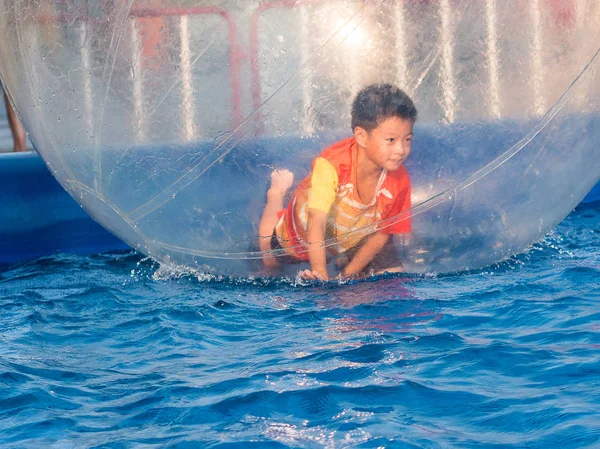Joven chico asiático jugando dentro de una bola flotante de agua caminando, Zo — Foto de Stock