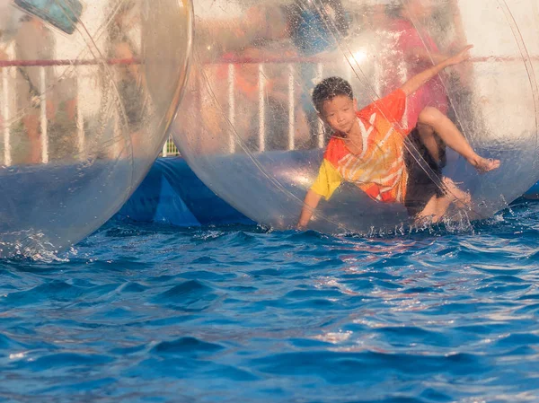 Jovem menino asiático jogando dentro de uma bola flutuante água andando, Zo — Fotografia de Stock