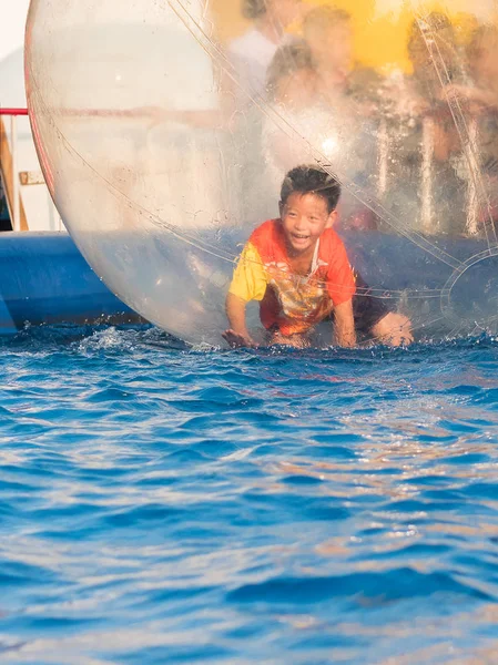 İçinde bir yüzen su topu yürüyüş oynayan genç Asyalı çocuk