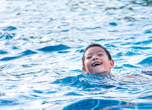 Asiático menino está jogando na piscina, flutuar — Fotografia de Stock