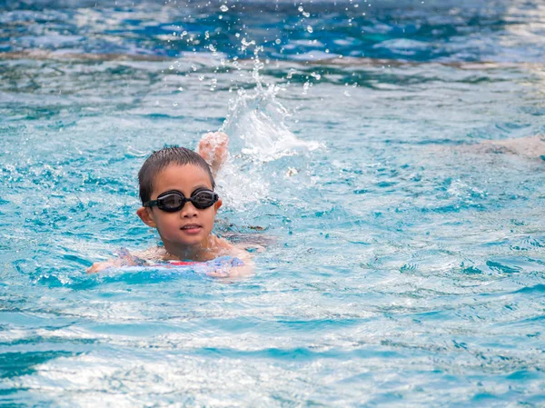 Ásia menino natação com o bordo no o piscina — Fotografia de Stock